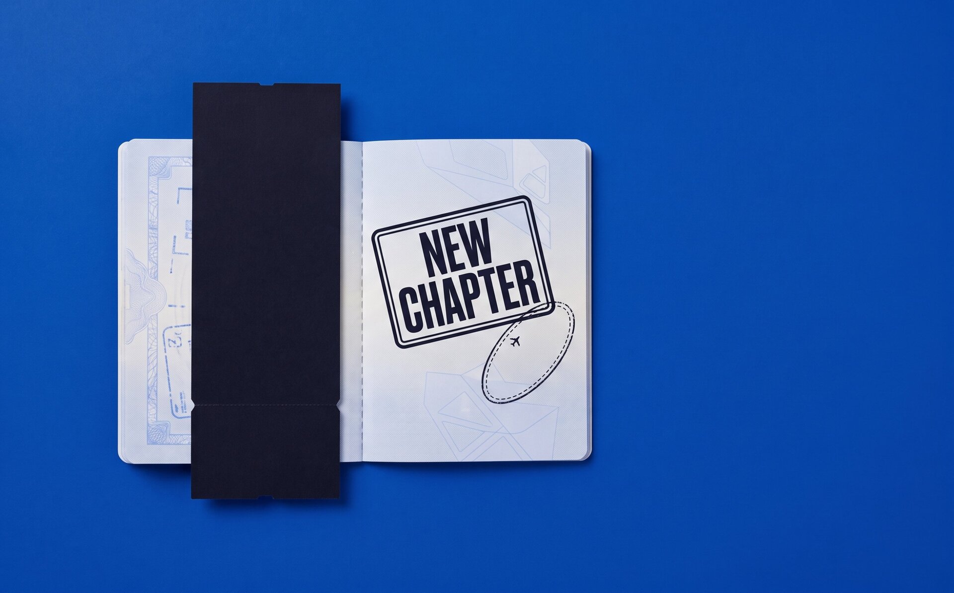 An open passport on a cobalt background with a ticket stub tucked inside and a tilted stamp reading NEW CHAPTER